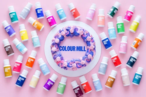 Colour Mill Food Colours 20ml oil-based food colouring bottles in assorted colours surrounding a decorated buttercream cake